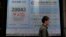 A man walks past an electronic board showing Hong Kong share index outside a local bank in Hong Kong, Jan. 11, 2016. 