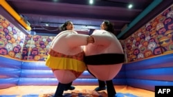 Visitors, wearing stuffed costumes, fight in the "sumo arena" at the HaHaHouse museum of laughter in central Zagreb, on January 21, 2025. (Photo by Damir SENCAR / AFP)