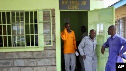 FILE - A prisoner, center, who aids his fellow inmates with writing legal documents, stands with them at Naivasha Prison in Kenya, Oct. 31, 2018.