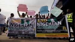 People hold banners and protest due to the economic hardship in Ibadan, Nigeria, Monday, February 19, 2024.