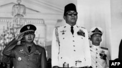 Presiden Soekarno (tengah) dalam peringatan HUT ke-21 Republik Indonesia di Lapangan Merdeka, depan Istana Merdeka, Jakarta, 17 Agustus 1966. Latar belakang: Pangkopkamtib Mohamed Soeharto (kiri). (AFP)