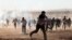 Turkish security forces use teargas and water cannons to disperse protesting local people as several hundred Syrian refugees wait at the border, in Suruc, Turkey, Sept. 21, 2014.