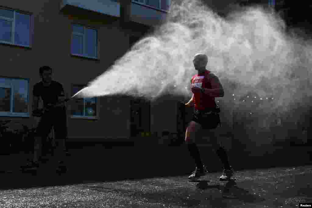 A participant of a half-marathon race is sprayed with water during hot weather in Omsk, Russia, May 30, 2021.