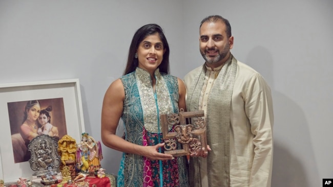 Sheetal Deo and her husband, Sanmeet Deo, hold a Hindu swastika symbol in their home in Syosset, N.Y., on Sunday, Nov. 13, 2022. (AP Photo/Andres Kudacki)