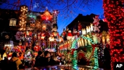 Turis melihat rumah yang dihiasi lampu Natal di kawasan Dyker Heights, Brooklyn, New York, Rabu, 21 Desember 2022. (Julia Nikhinson/AP)