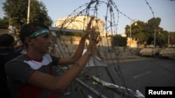 A member of the Muslim Brotherhood and supporter of ousted Egyptian President Mohamed Morsi holds onto barbed wire as he shouts slogans against the military and interior ministry near El-Thadiya presidential palace in Cairo, Sept. 20, 2013.