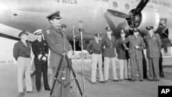제1공수특무부대 사령관인 에드워드 H. 알렉산더 준장이 1949년 9월 30일 서독 프랑크푸르트에서 '비틀스 작전(Operation Vittles)'과 베를린 공수작전의 종식을 기념하는 행사에서 마이크를 잡고 연설을 하고 있다. 오른쪽에는 수송기 승무원들이 있다.