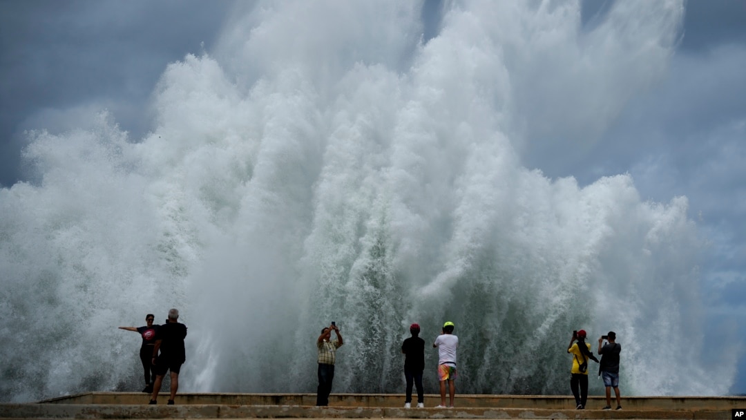 People take photos of the spray from waves crashing against the Malecon seawall, brought by the passing of Hurricane Milton in the Gulf of Mexico in Havana, Cuba, Oct. 9, 2024