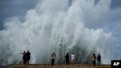 People take photos of the spray from waves crashing against the Malecon seawall, brought by the passing of Hurricane Milton in the Gulf of Mexico in Havana, Cuba, Oct. 9, 2024