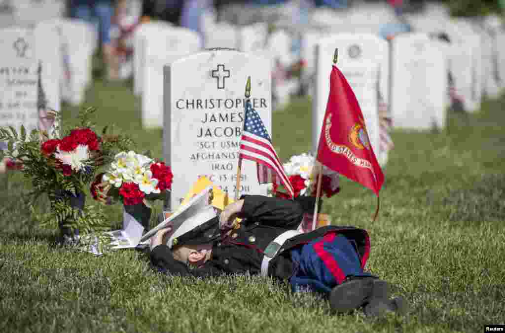 Christian Jacobs, 4, of Hertford, North Carolina, lies on the grave of his father, Christian James Jacob, during Memorial Day celebrations at Arlington National Cemetery in Arlington, Virginia, May 25, 2015.