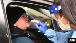 Medical staff perform a test for COVID-19 on a driver at a drive-through testing site in Melbourne, Australia, on May 1, 2020. 