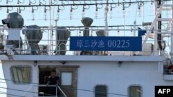 A Chinese national looks out from aboard a Chinese vessel identified by the Philippines as “maritime militia” during the Philippine coast guard’s mission to deliver provisions at Second Thomas Shoal in the South China Sea on Nov. 10, 2023.