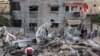 Palestinians check the damage amid the rubble of a destroyed building, following Israeli airstrikes on the northern Gaza Strip town of Beit Lahia, early May 13, 2021.