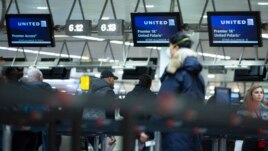 A man wears a protective mask as he waits to check into a flight to the United States in the main terminal of Brussels International Airport in Brussels, Friday, March 13, 2020.