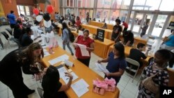 FILE - People attend a job fair at Dolphin Mall in Miami. The federal government issues its October jobs report Friday, Nov. 6, 2015. 