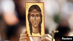 Un fiel sostiene una imagen que representa a Kateri Tekakwitha, el primer americano declarado santo por el Papa Benedicto XVI. 