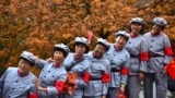 Women in replica red army uniforms have their picture taken as autumn leaves cover maple trees in Fragrant Hills Park in Beijing, China.