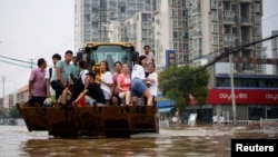 河南郑州暴雨后居民乘斗车疏散。（2021年7月23日）