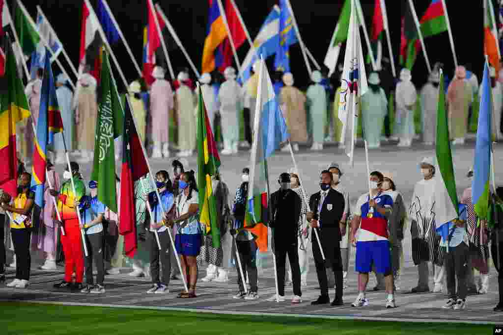 Athletes and volunteers carry flags during the closing ceremony in the Olympic Stadium at the 2020 Summer Olympics, Sunday, Aug. 8, 2021, in Tokyo, Japan. (AP Photo/Aaron Favila)