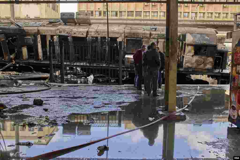 Officials stand next to the burned wreckage of a locomotive after the crash at Cairo’s main railway station. The crash set off a massive explosion when the locomotive’s fuel tank exploded. (H. Elrasam/VOA)