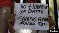 A woman holds a placard that reads "No more hunger. Stop. Change. Out Maduro Out" — a reference to President Nicolas Maduro — during a gathering of opposition supporters in Caracas, Venezuela, March 17, 2018. 