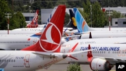 FILE - Dozens of grounded Boeing 737 MAX airplanes crowd a parking area adjacent to Boeing Field in Seattle, June 27, 2019. 