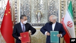 Iranian Foreign Minister Mohammad Javad Zarif, right, and his Chinese counterpart, Wang Yi, pose for a photo after signing a bilateral agreement, in Tehran, Iran, March 27, 2021.