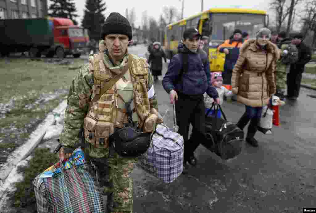 A member of the Ukrainian armed forces assists local residents onto a bus to flee the military conflict, in Debaltseve, eastern Ukraine. Convoys of buses converged from two sides on the town&nbsp; after separatist rebels and government forces appeared to have patched together a truce to allow civilians to be evacuated.