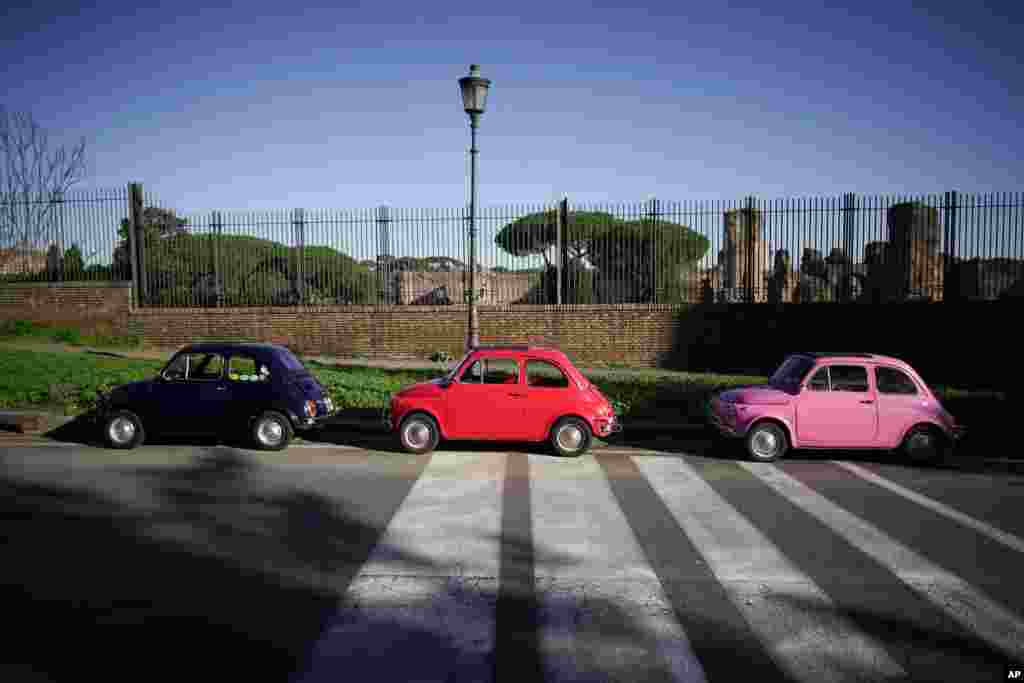 Three vintage FIAT 500 cars are parked in front of the ruins of the Ancient Roman Caracalla baths, in Rome, Italy.