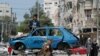 A Palestinian man rides a donkey-drawn cart transporting an old car to a scrap yard, in Gaza City.