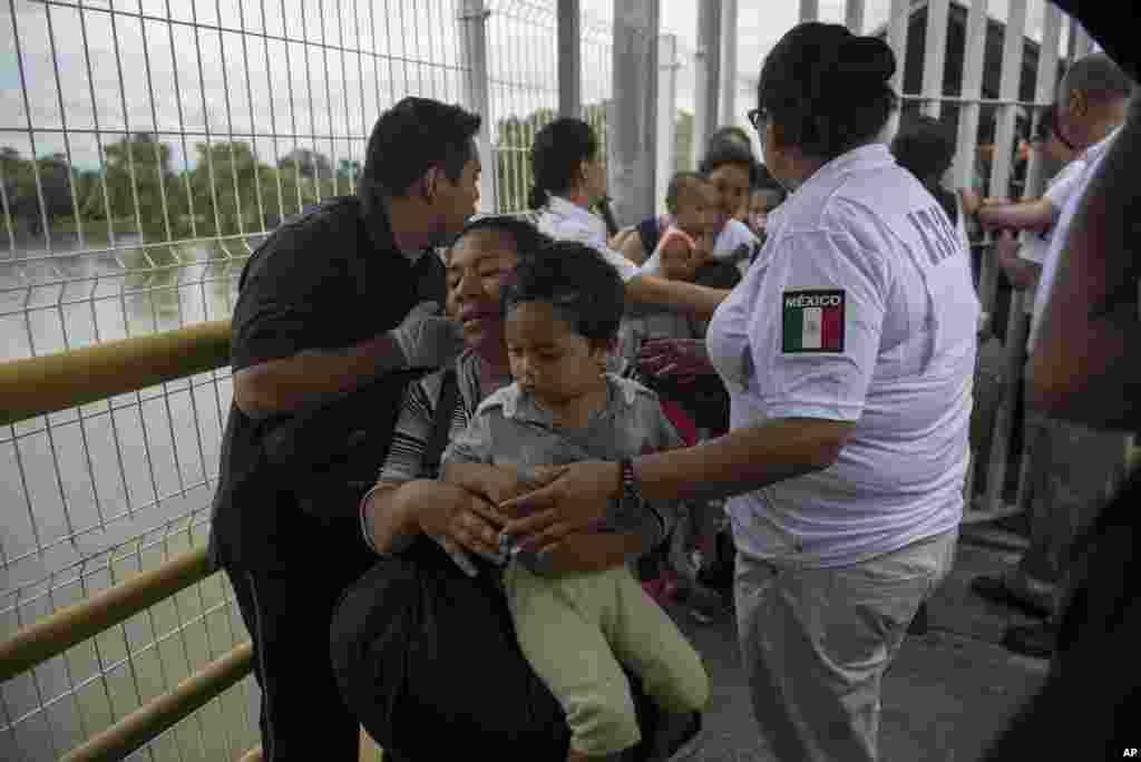A Honduras migrant mother and her son walk through the bridge after crossing the border between Guatemala and Mexico, in Ciudad Hidalgo, Mexico, Oct. 20, 2018. Mexican officials are refusing to yield to demands from the caravan of Central American migrants that they be allowed to enter the country en masse but announced they would hand out numbers to those waiting to cross and allow them to enter in small groups.