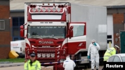 FILE - Police are seen at the scene where bodies were discovered in a truck container, in Grays, Essex, Britain, Oct. 23, 2019. 