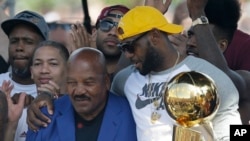 Lebron James de Cavaliers de Cleveland, avec le trophée du champion de la NBA 2016, tient à l’épaule Brown ‘Jim Brown, un ancien de l’équipe, à Cleveland, 22 juin 2016.