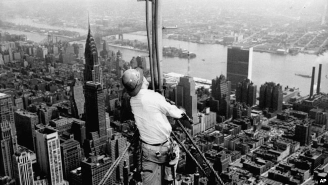 High over Manhattan, a workman is busy on construction for the Empire State Building's new 217 foot multiple television tower, September 28, 1950. (AP Photo)