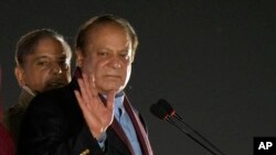 Pakistan's former Prime Minister Nawaz Sharif, returning to his native Lahore, Paksistan, on Oct. 21, 2023, after four years of self-imposed exile in London, waves as his brother Shehbaz Sharif watches.