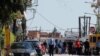 A police officer wearing a protective face mask walks near members of a Roma community where several cases of the coronavirus have been detected, in Larissa, Greece, April 10, 2020.