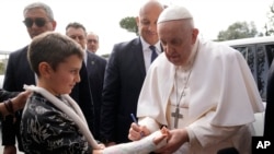 Paus Fransiskus menandatangani gips seorang anak saat ia meninggalkan Rumah Sakit Universitas Agostino Gemelli di Roma, Sabtu, 1 April 2023, setelah menjalani pengobatan bronkitis. (Foto: AP)