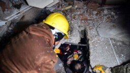 Petugas darurat dan petugas medis menyelamatkan seorang perempuan dari puing-puing bangunan yang runtuh di Elbistan, Kahramanmaras, Turki selatan, Selasa, 7 Februari 2023. (Foto: via AP)