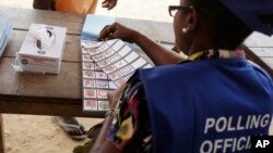 An electoral official tears a presidential ballot paper during the Presidential and parliamentary election, in Kibi, eastern Ghana, Dec. 7, 2016. 