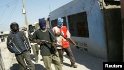 FILE - Haitian vigilante gunmen patrol their neighborhood in the Cite de Dieu (City of God) slum of Port-au-Prince, Haiti, Feb. 25, 2005.