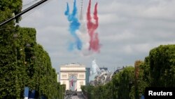 Des Alphajets de l'Armée de l'Air française volent en dégageant une traînées de fumée rouge, blanc et bleu, couleurs du drapeau national français, survolant les Champs-Elysées au cours de la traditionnelle du défilé de jour de la Bastille à Paris, 14 juillet