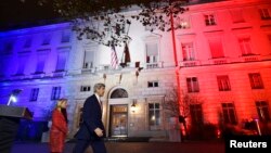 Menteri Luar Negeri AS John Kerry bersama Duta Besar AS untuk Perancis Jane D. Hartley, meninggalkan Kedubes AS yang dihiasi sinar berwarna bendera nasional Perancis (16/11). (Reuters/Dominique Faget)