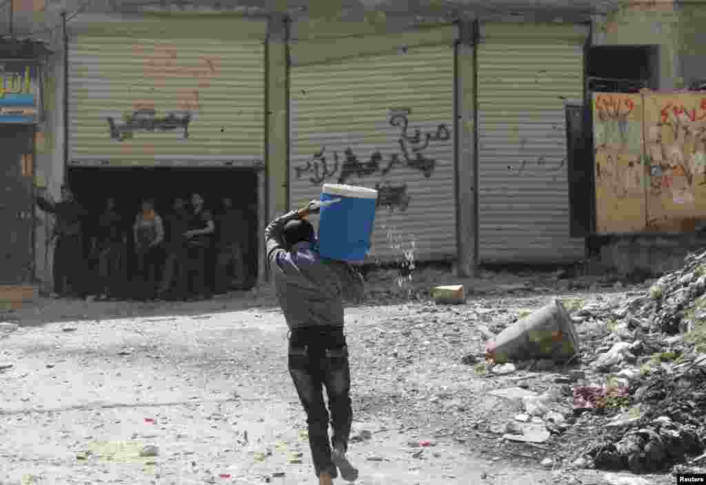 A man holding a water cooler runs to avoid a sniper in Aleppo&#39;s Salaheddine neighborhood, April 28, 2013. 