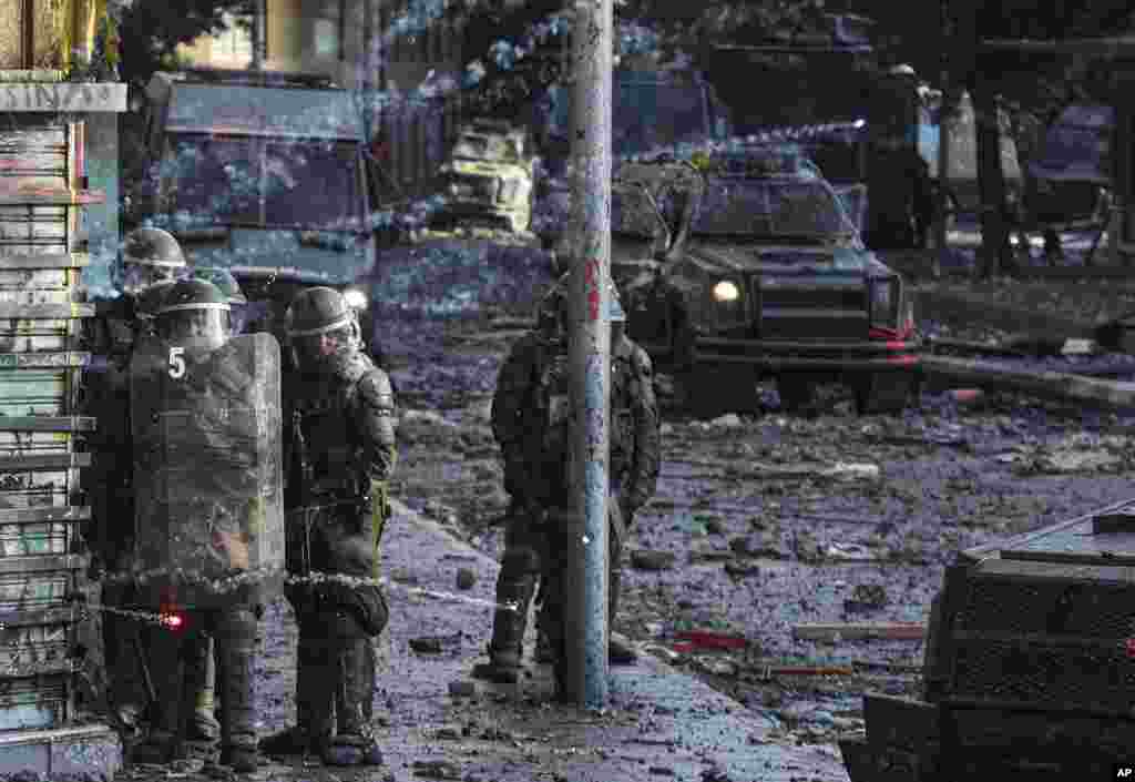 Policías chilenos se parapetan en una esquina mientras se enfrentan a manifestantes descontentos en Santiago de Chile, el 12 de noviembre de 2019.