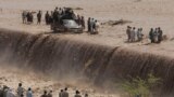 Pakistani villagers wade across a flooded road after heavy rain on the outskirts of Peshawar. Flash floods triggered by torrential rains killed dozens of people in northwest Pakistan, officials said.