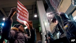 A protester stands facing police officers at an entrance of Terminal 4 at John F. Kennedy International Airport in New York, Jan. 28, 2017, after earlier in the day two Iraqi refugees were detained while trying to enter the country.