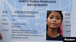 Seorang aktivis anti-korupsi memegang poster berbentuk KTP dalam unjuk rasa menuntut penyelidikan dugaan korupsi pengadaan e-ktp oleh para pejabat, di Jakarta, 19 Maret 2017. (Foto: Reuters) 