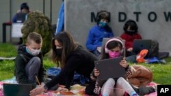 Sarah Swanson (centro) ayuda a sus hijos Hayes, de tercer grado, y Larkin, de primer grado, a estudiar durante una clase a distancia por Zoom, en San Francisco, California. Febrero 18 de 2021.