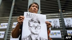 FILE - An activist holds an illustration of Simon Cheng during a gathering outside the British Consulate-General building in Hong Kong, Aug. 21, 2019.