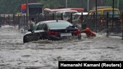 Seorang pria mendorong mobil, terjebak di jalan yang banjir, saat hujan lebat di Mumbai, India, 4 Juli 2020. (Foto: REUTERS/Hemanshi Kamani)